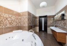 Panele winylowe a płytki ceramiczne w łazience – co lepsze na wodę i parę Nowoczesna łazienka z okrągłą wanną, umywalką i drewnianą szafką