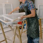 Stolarz w fartuchu pracuje przy drewnianym stole w pracowni near okna